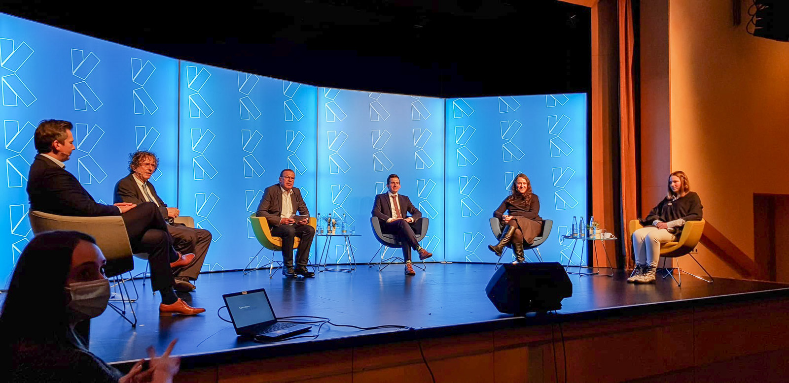 Podiumsdiskussion auf einer blau beleuchteten Bühne beim Neujahrsempfang