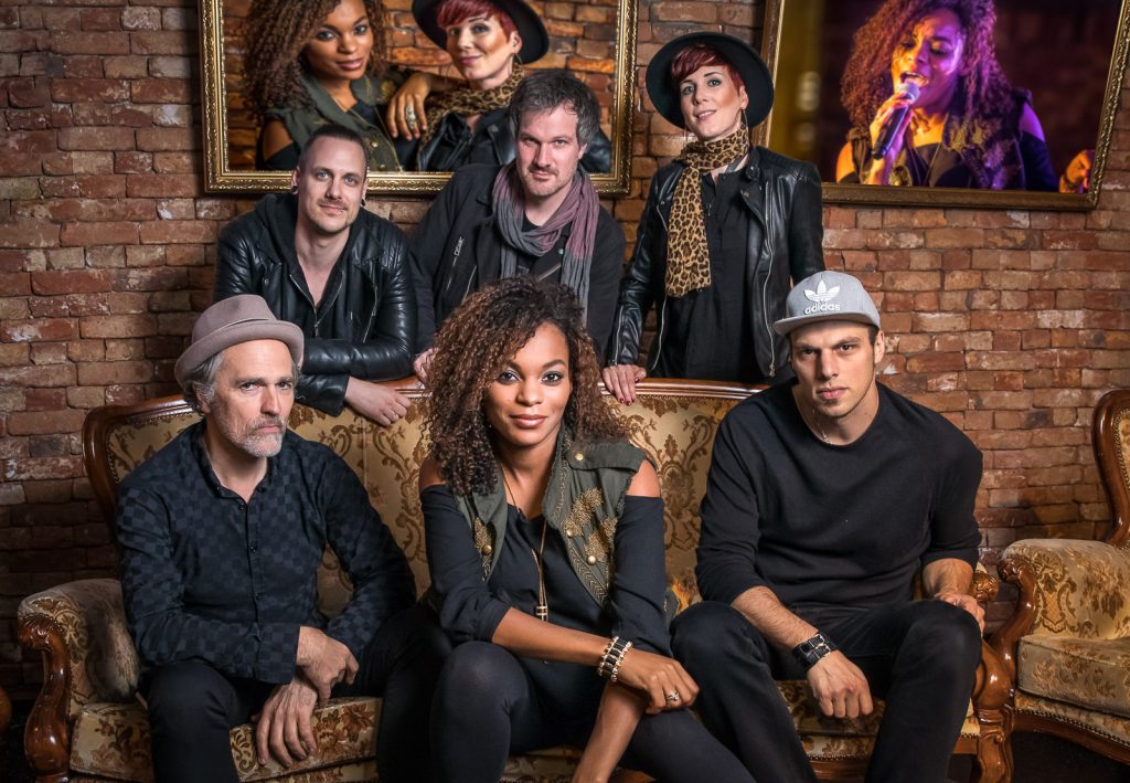 Sechsköpfige Band auf einem Barocksofa vor Backsteinwand