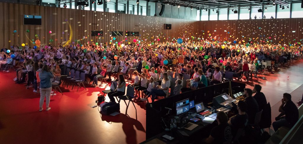 Voll besetzte Halle mit bunten Luftballons während einer Show