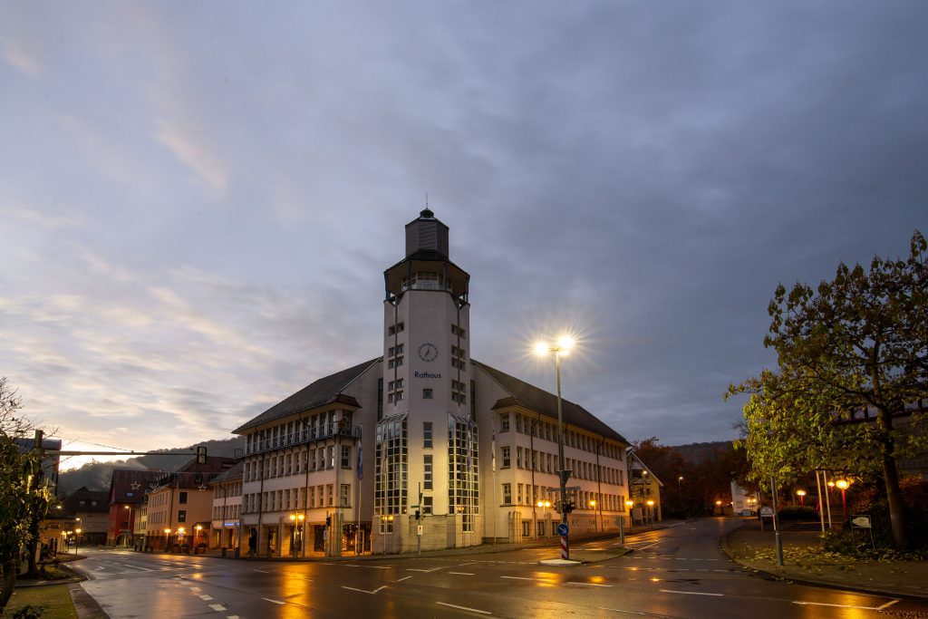 Rathaus Künzelsau in der Abenddämmerung mit beleuchteten Fenstern und Straßenlaternen