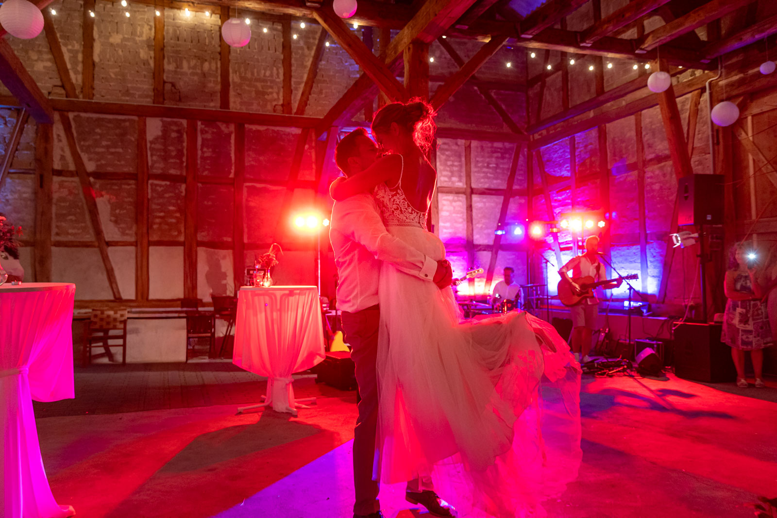 Hochzeitstanz in einer Scheune mit rotem Licht und Liveband