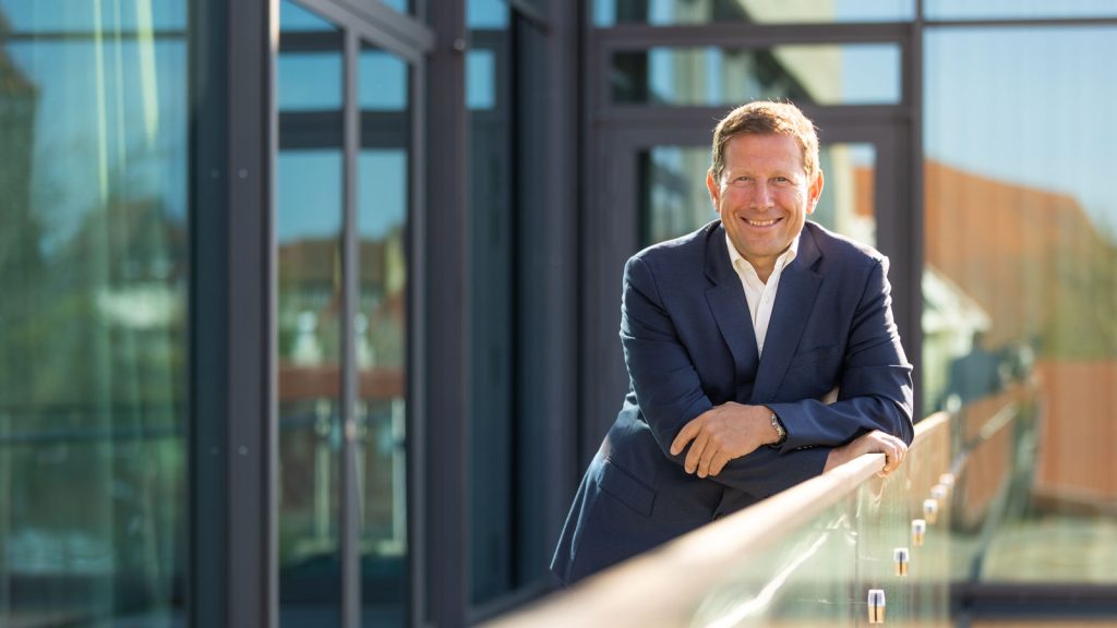 Unternehmer im Anzug an einem Geländer vor einer Glasfassade